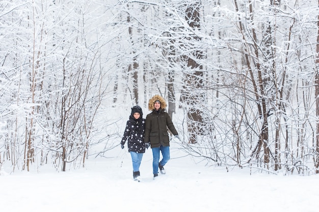 Jeune couple marchant dans un parc enneigé. L'hiver.