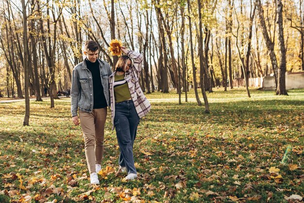 Photo jeune couple marchant à l'extérieur du parc embrassant souriant s'embrassant riant passer du temps ensemble automne