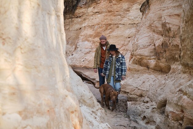 Jeune couple marchant avec leur chien le long des rochers à l'extérieur