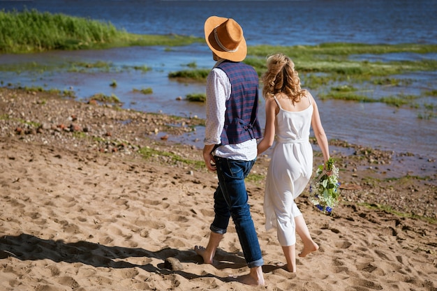 Jeune couple marchant le long de la plage par une journée d'été ensoleillée