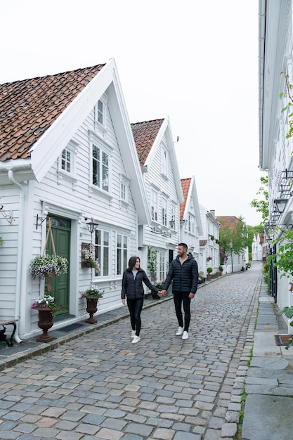 Jeune couple marchant le long d'une rue à Stavanger avec des maisons blanches scandinaves typiques en Norvège
