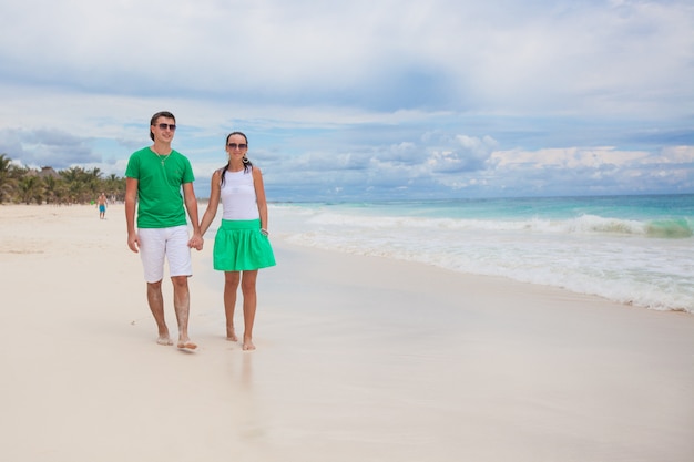 Jeune couple marchant sur une plage exotique en journée ensoleillée