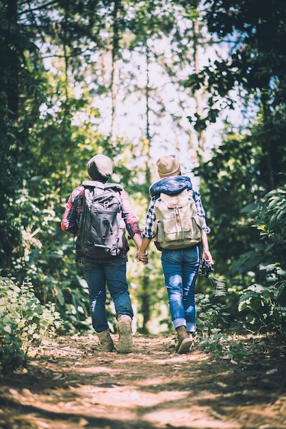 Jeune couple marchant avec des sacs à dos en forêt