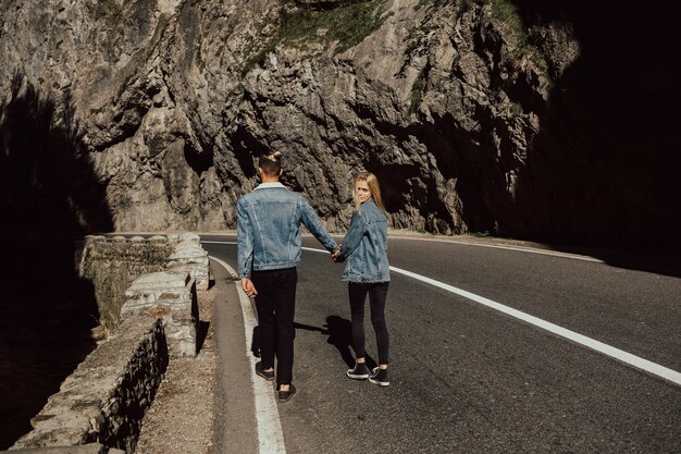 Jeune couple marche sur la route dans la montagne.