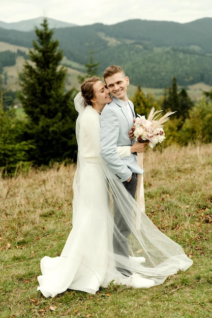 Jeune couple de mariage étreignant doucement après la cérémonie de mariage dans les montagnes belle journée de mariage