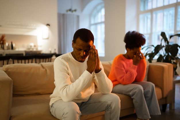 Jeune couple marié africain bouleversé assis sur un canapé à la maison et se sentant bouleversé après une querelle