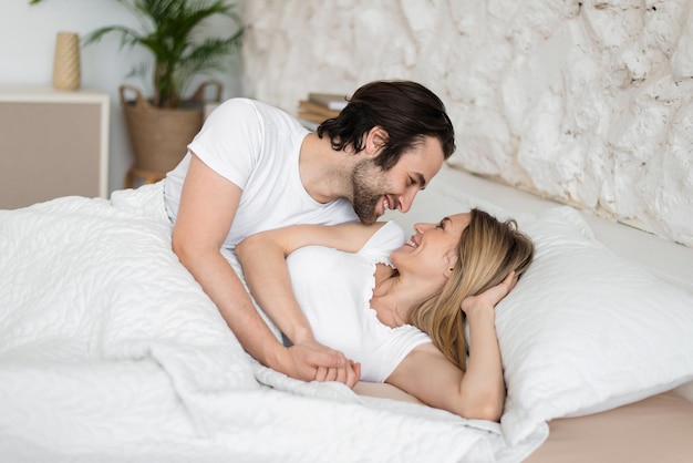 Jeune couple marié aimant se détendre en se regardant dans son lit à la maison se sentant heureux le matin