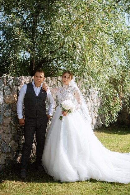 Jeune couple le marié en costume à carreaux et la mariée en robe blanche chic