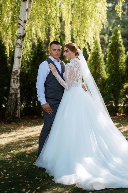 Jeune couple le marié en costume à carreaux et la mariée en robe blanche chic