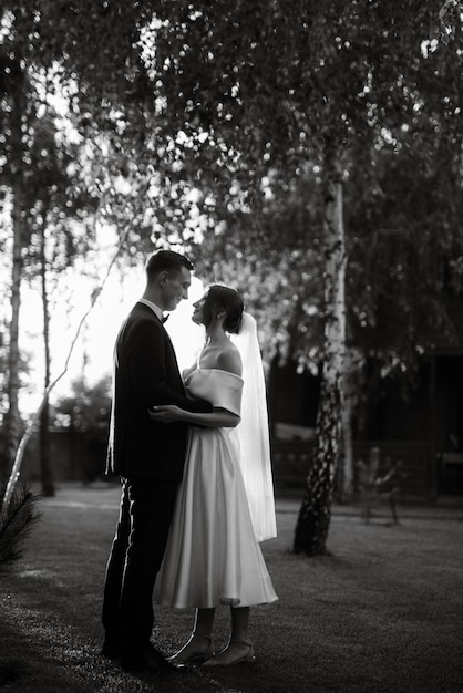 Jeune couple le marié en costume noir et la mariée en robe courte blanche