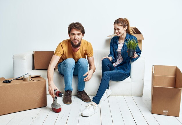 Jeune couple marié dans un nouvel appartement sur un canapé blanc boîtes avec des choses en mouvement photo de haute qualité