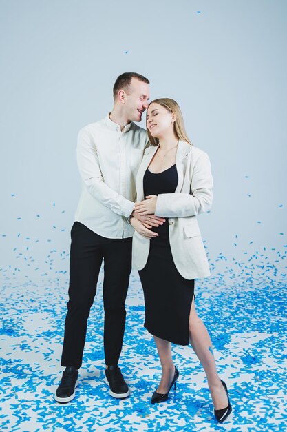 Jeune couple marié heureux s'embrassant dans des confettis bleus Un couple amoureux se réjouit et s'amuse Séance photo de genre