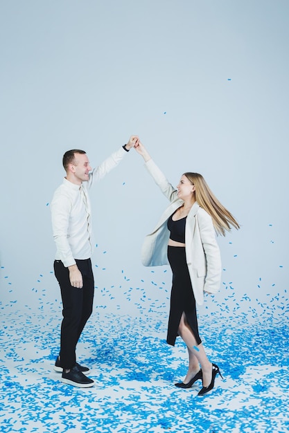 Jeune couple marié heureux s'embrassant dans des confettis bleus Un couple amoureux se réjouit et s'amuse Séance photo de genre