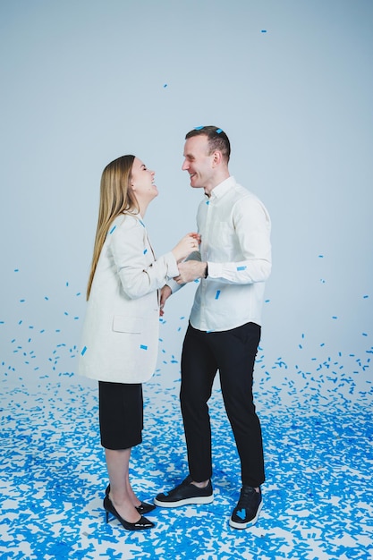 Jeune couple marié heureux s'embrassant dans des confettis bleus Un couple amoureux se réjouit et s'amuse Séance photo de genre