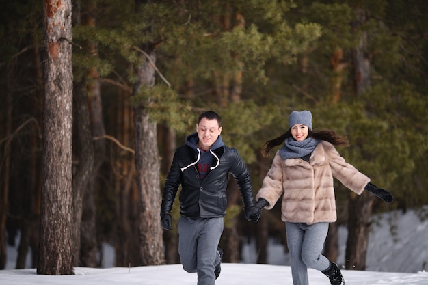 Photo jeune couple marié en hiver dans une forêt enneigée se tiennent la main