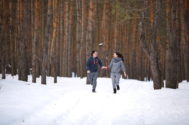 Jeune couple marié en hiver dans une forêt enneigée se tiennent la main