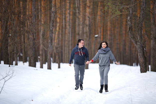 Jeune couple marié en hiver dans une forêt enneigée se tiennent la main