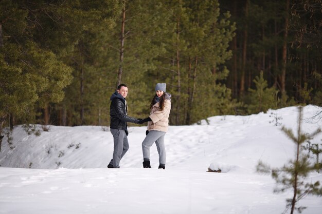 Jeune couple marié en hiver dans une forêt enneigée se tiennent la main