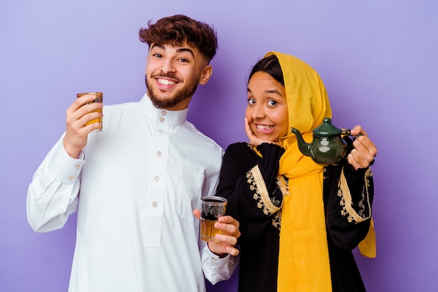 Photo jeune couple marocain buvant du thé célébrant le mois du ramadan isolé sur fond violet