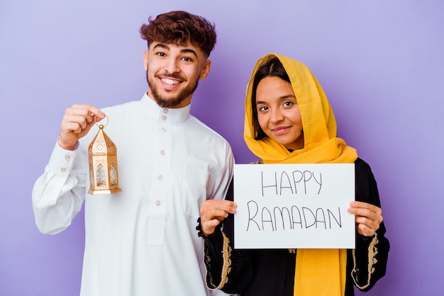 Jeune couple marocain portant un costume arabe typique célébrant le Ramadan isolé sur fond violet