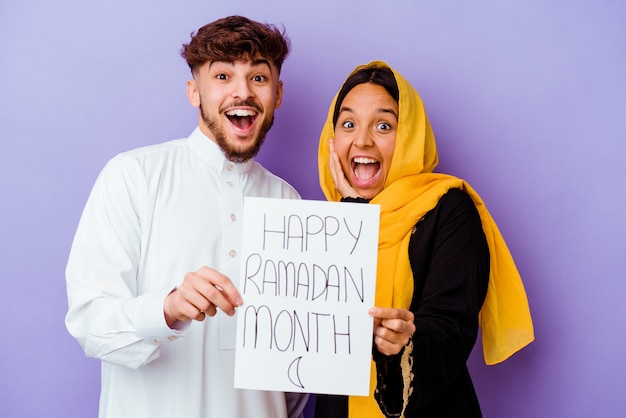 Jeune couple marocain portant un costume arabe typique célébrant le Ramadan isolé sur fond violet