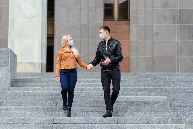 Jeune couple en masques sur la rue de la ville.