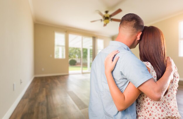 Un jeune couple de militaires regarde une pièce vide de leur nouvelle maison.