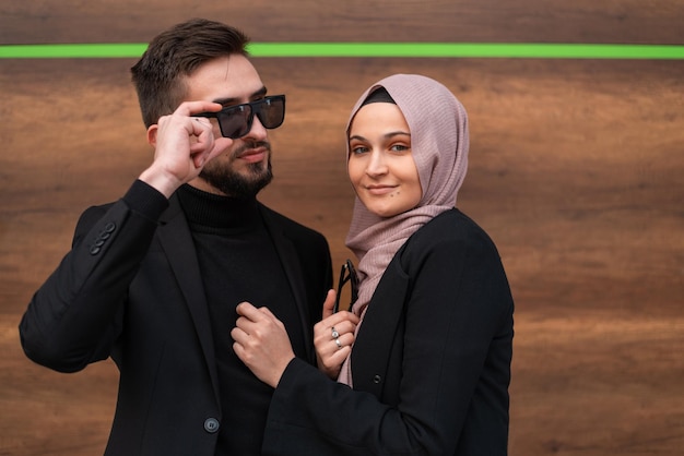 Un jeune couple à la mode musulman heureux posant à l'extérieur