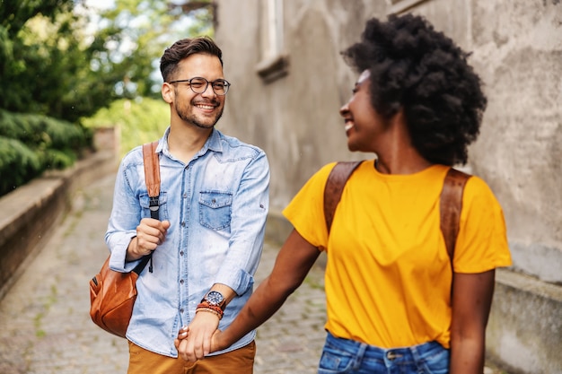 Jeune couple multiculturel mignon se promener dans une vieille partie de la ville.