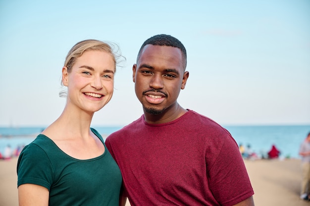 jeune couple multiethnique regardant la caméra à la plage