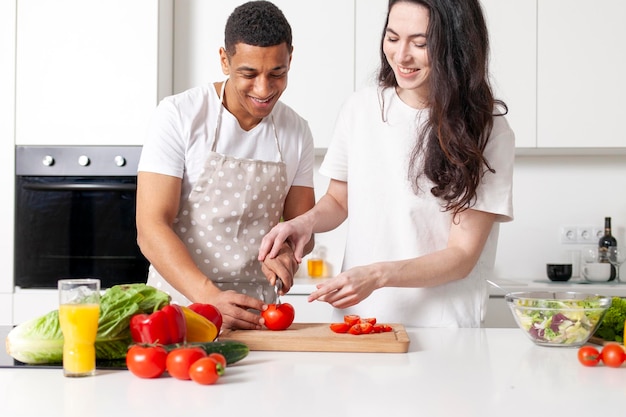 jeune couple multiracial préparant une salade de légumes et de légumes verts