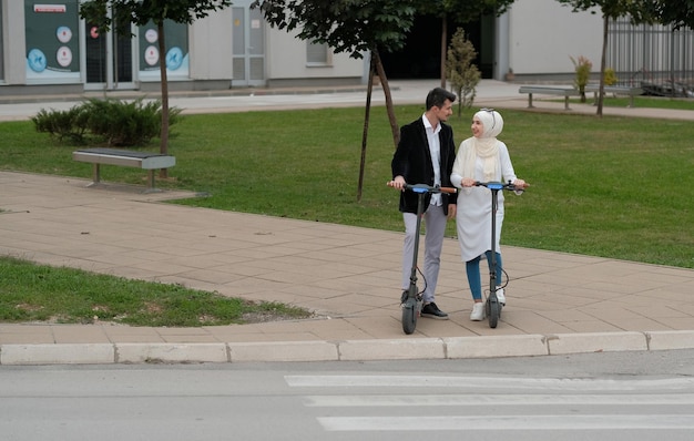 Jeune couple musulman heureux faisant du scooter électrique dans la rue de la ville