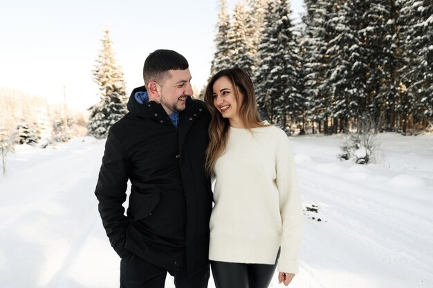 Jeune couple sur la neige en hiver dans le concept d'amour et de vacances du parc couple heureux étreignant et riant à l'extérieur en hiver