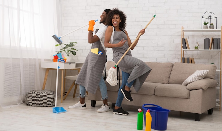 Photo un jeune couple nettoie la maison en s'amusant avec un balai et un balai.
