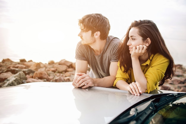 Jeune couple par une voiture de sport garée sur la plage. Romance et amour dans un voyage en voiture.