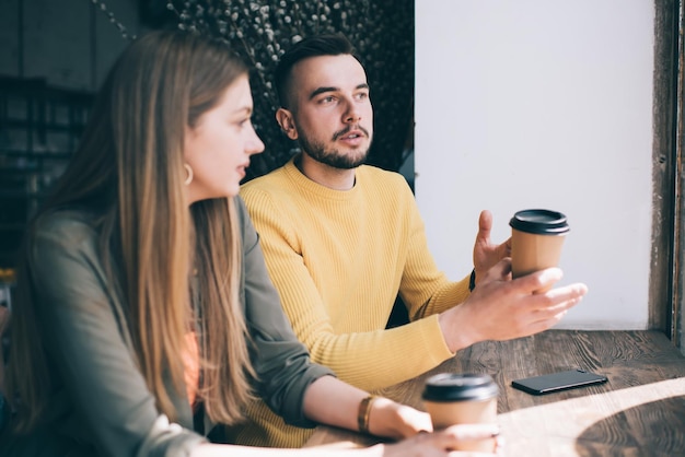 Jeune couple parlant en buvant du café au café