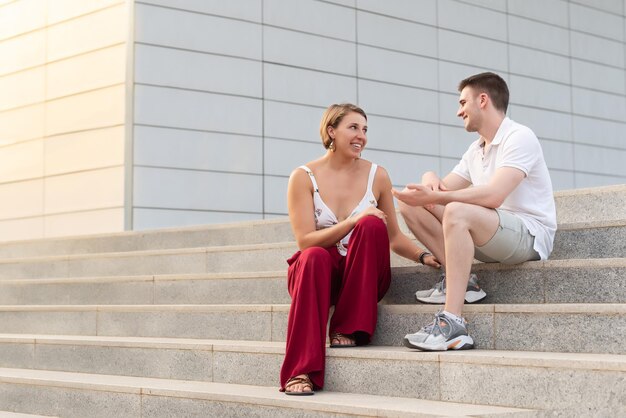 Jeune couple parlant d'une manière détendue assis sur des escaliers après avoir quitté le travail