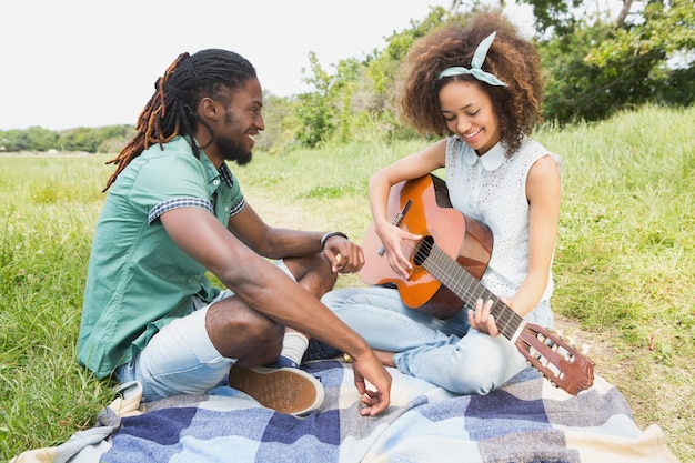 Jeune couple sur un pique-nique, jouer de la guitare