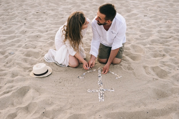 Photo un jeune couple sur une plage de sable a posé une ancre de coquillages