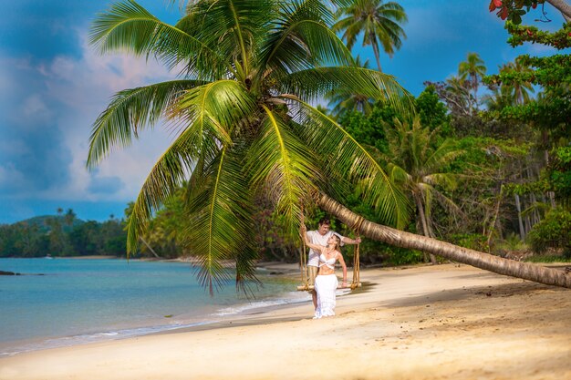 Jeune couple sur la plage sous un palmier