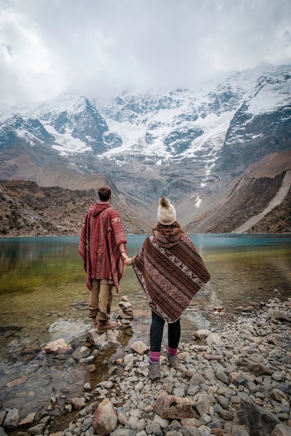 Un jeune couple avec des ponchos en vacances à Laguna Humantay Pérou