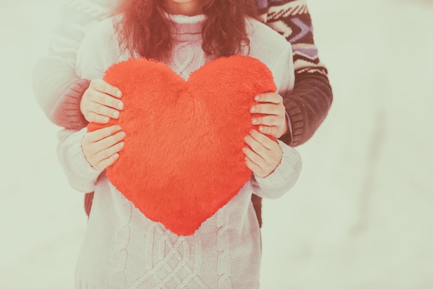 Jeune couple portant des chandails avec coeur étreignant à l'extérieur en hiver couleur Vintage