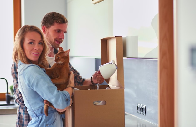 Jeune couple portant une grande boîte en carton à la nouvelle maison de déménagement