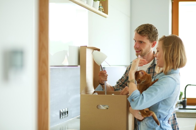 Jeune couple portant une grande boîte en carton à la nouvelle maison de déménagement