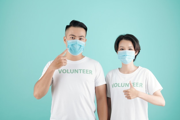 Jeune couple portant un masque médical invitant d'autres personnes à travailler comme bénévoles et à aider les gens pendant la pandémie de coronavirus