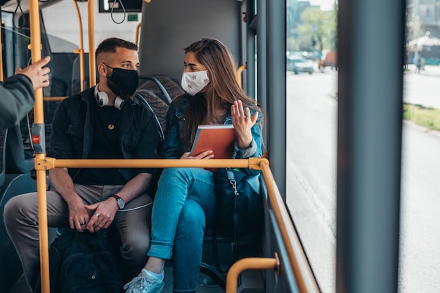 Jeune couple portant des masques de protection dans un bus