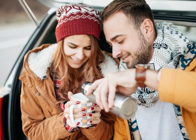 Jeune couple portant des vêtements chauds, buvant du thé chaud un jour d'hiver.