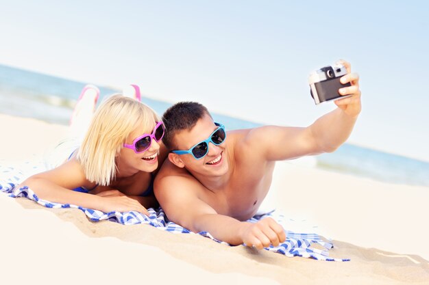 un jeune couple prenant des photos à la plage