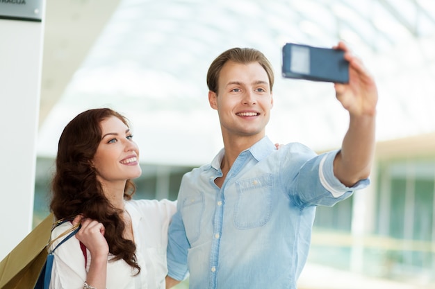 Jeune couple prenant un selfie dans un centre commercial