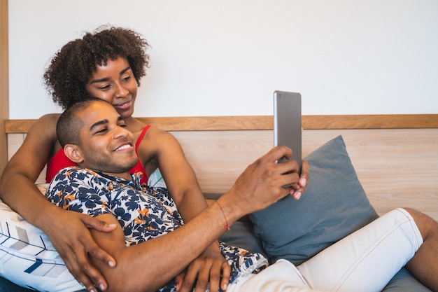 Jeune couple prenant un selfie avec tablette numérique à la maison